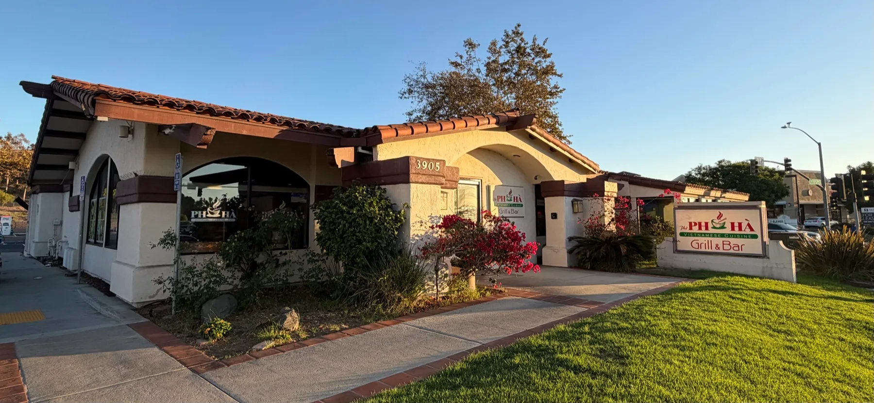 The Phở Hà Grill & Bar building in Oceanside, with its tile roof and street sign